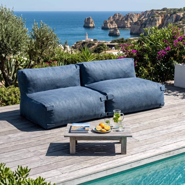 Zweisitzer-Outdoor-Lounge-Sofa auf einer Holzterrasse am Pool mit Blick auf das Meer.