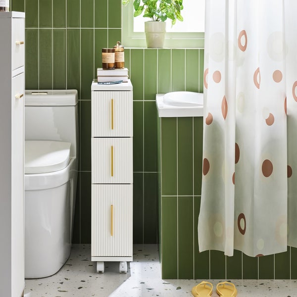 Badezimmer mit Toilette, Waschbecken und einem schmalen Badezimmerschrank mit drei Schubladen