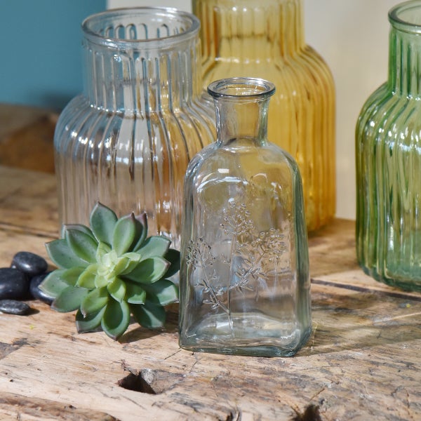 Dekorative Glasvasen mit Sukkulente und Steinen auf einem Holztisch