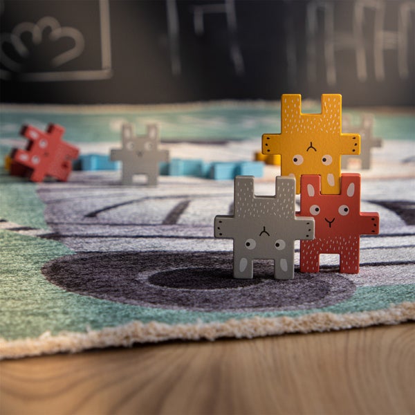 Set aus Holzfiguren in Hasenform zum Stapeln auf einem Kinderspielteppich