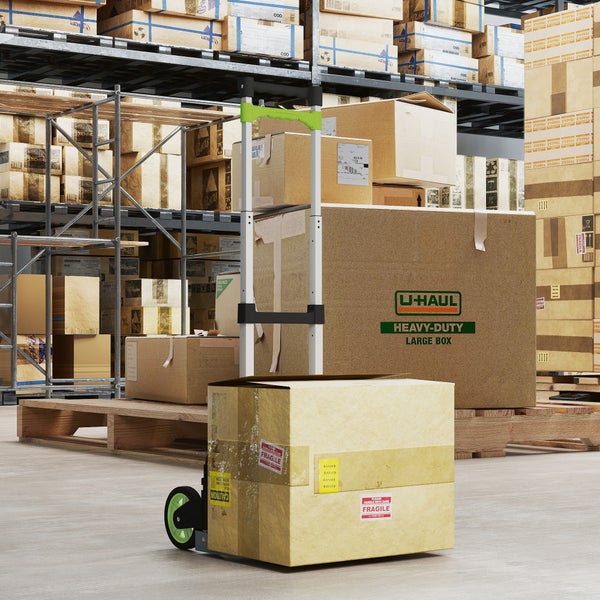 Lagerhalle mit Kartons auf Regalen und ein beladener Transportwagen mit Kartons