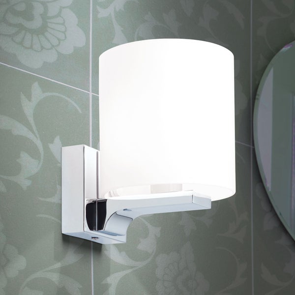 Moderne Wandleuchte mit zylindrischem Glasschirm und verchromter Metallhalterung montiert an einer gefliesten Wand.