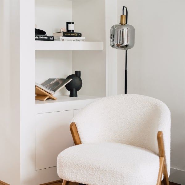 Einrichtungsszene mit Sessel, Stehlampe und Regalen