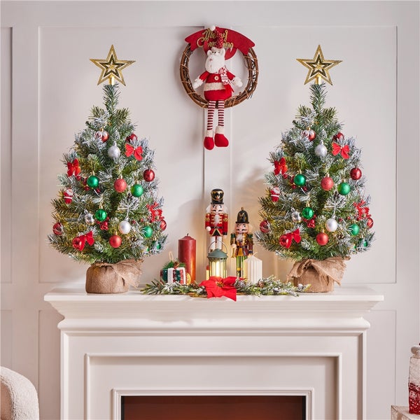 Dekorativer Kaminsims mit zwei kleinen Weihnachtsbäumen, Nussknackern und Weihnachtsschmuck.