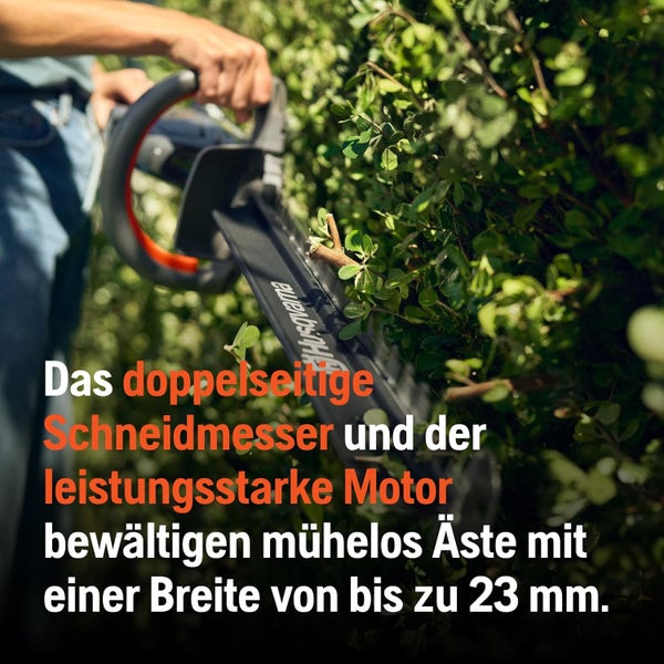 Person schneidet Hecke mit einer Heckenschere.