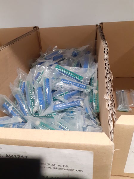 Mehrere einzeln in Folie verpackte Anschlussplatinen für Elektroinstallationen in einem Pappkarton.