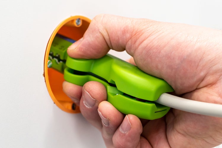 Hand führt eine Kabelinstallation in einer Unterputzdose durch