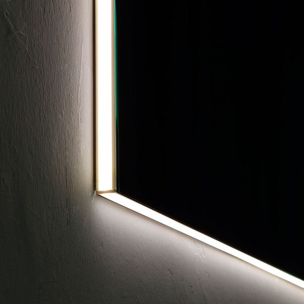 Detailaufnahme einer Spiegelecke mit integrierter LED-Beleuchtung und indirektem Lichteffekt auf einer strukturierten Wand.