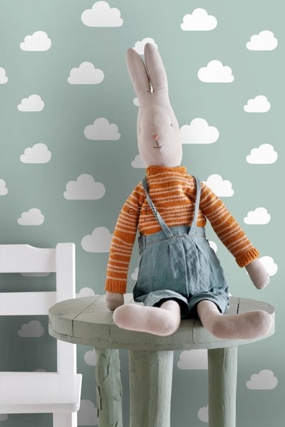 Stofftier Hase mit gestreiftem Pullover und Latzhose auf einem Tisch