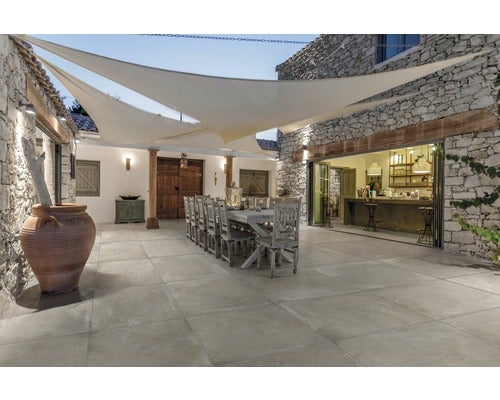 Außenbereich mit Fliesenboden, Steingebäude, Holztisch und Sonnensegel