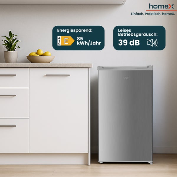 Kompakter silberfarbener Kühlschrank von HomeX neben einem weißen Küchenschrank, mit Informationen zum Energieverbrauch und Geräuschpegel