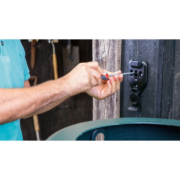 Eine Person befestigt mit einem Schraubendreher eine Halterung an einer Holzwand.