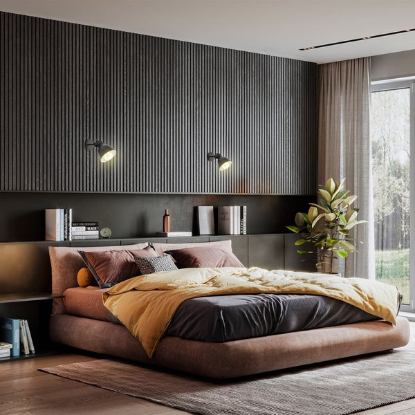 Modernes Schlafzimmer mit Wandpaneelen aus dunklen Holzlamellen, einem großen Polsterbett, zwei Wandleuchten und einem Ausblick ins Grüne.