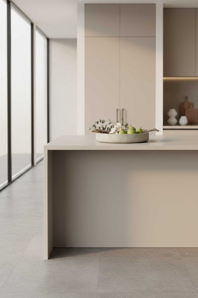 Moderne helle Küche mit minimalistischer Kücheninsel in Beige, grauen Bodenfliesen und großen Fensterfronten.