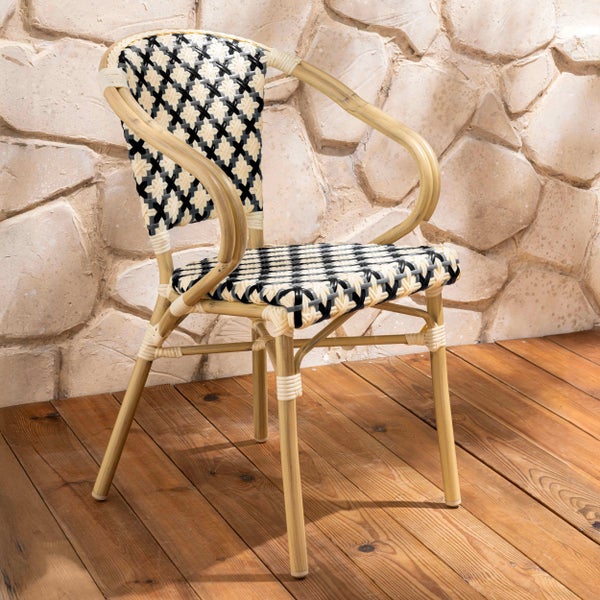 Bistrostuhl mit schwarz-weißem Geflecht und Gestell in Rattan-Optik auf einer Holzterrasse vor einer Steinwand.