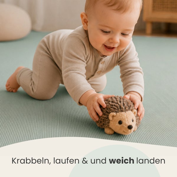 Ein Kleinkind krabbelt auf einer weichen Bodenmatte und spielt mit einem weichen Igel Stofftier.