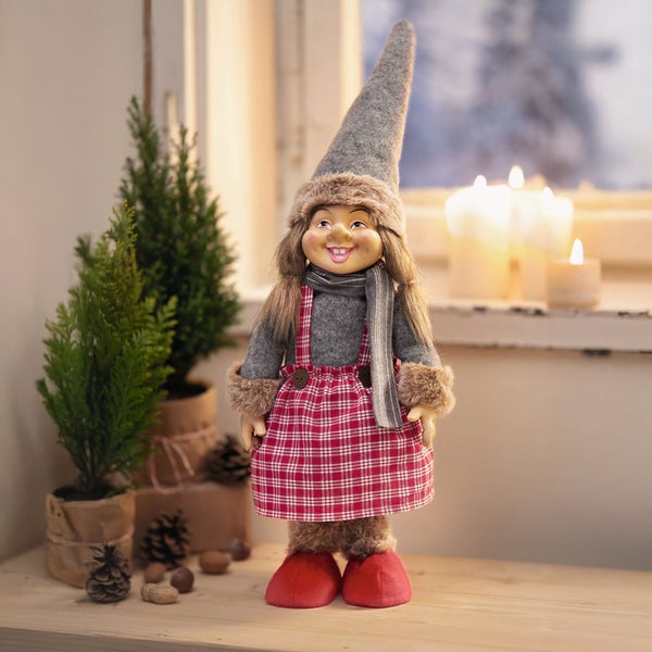 Dekorative Elfe mit kariertem Kleid und Weihnachtsbäumen im Hintergrund