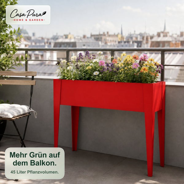 Rotes Hochbeet auf Beinen auf einem Balkon, bepflanzt mit bunten Blumen vor einer Stadtkulisse.