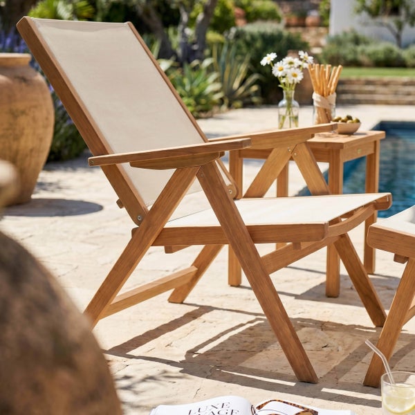 Verstellbarer Gartenstuhl aus Teakholz mit Textilbespannung auf einer hellen Steinterrasse am Pool mit passendem Beistelltisch.