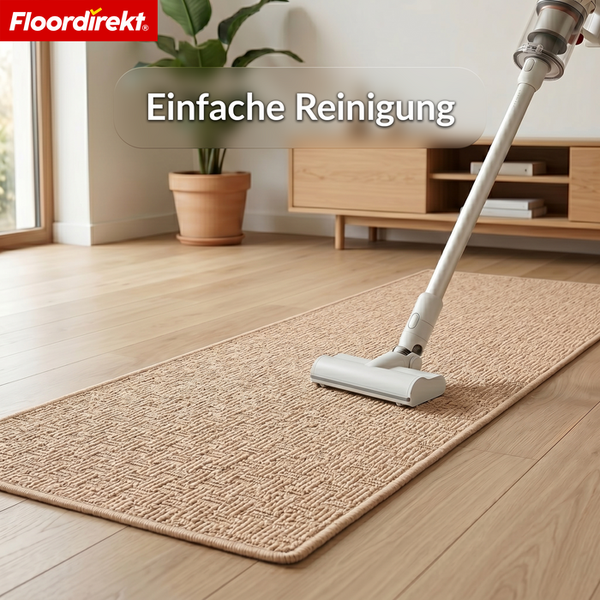Staubsauger reinigt einen strukturierten Teppichläufer auf Holzboden in einem hellen Wohnzimmer. Einfache Reinigung. Floordirekt Logo.