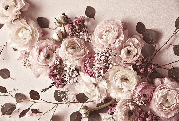 Wanddekoration mit einem Arrangement aus Ranunkeln, Schleierkraut und Eukalyptusblättern. Florales Design für eine helle, freundliche Atmosphäre.