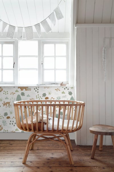 Babyzimmer mit Rattanwiege, Fenster, Dekoration und hölzernem Hocker