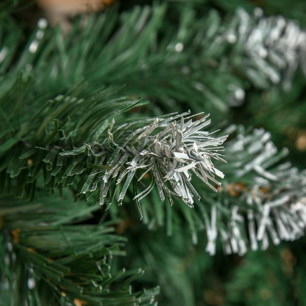 Nahaufnahme eines grünen künstlichen Weihnachtsbaumzweigs mit weiß beschneiten Spitzen.