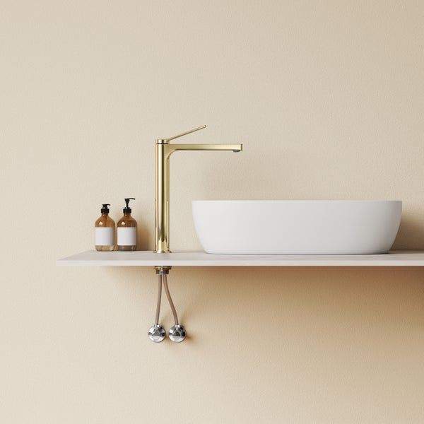 Ein Aufsatzwaschbecken mit einer goldenen Waschtischarmatur auf einem Wandboard und zwei Seifenspendern im Badezimmer.