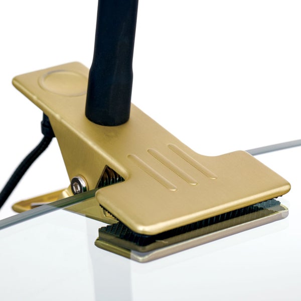 Nahaufnahme einer goldenen Klemmlampe, die an einer Glasplatte befestigt ist
