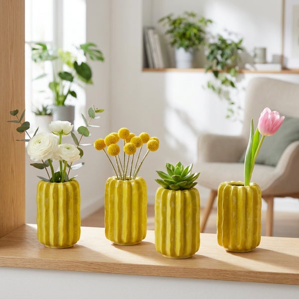 Vier kaktusförmige Keramikvasen stehen auf einem Regalbrett, dekoriert mit verschiedenen Blumen und einer Sukkulente in einem hellen Wohnraum.