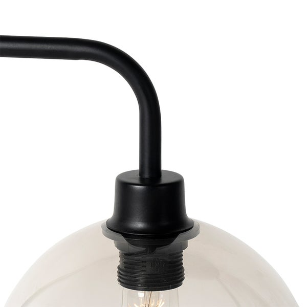 Detailansicht einer schwarzen Metalllampe mit gebogenem Arm und gläsernem Lampenschirm.