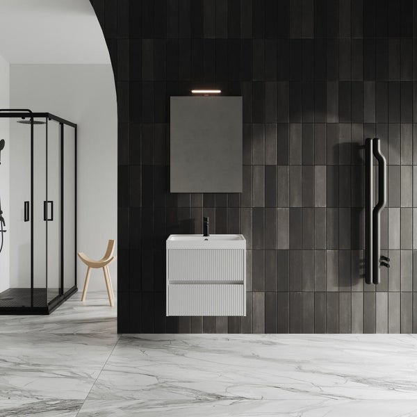 Modernes Badezimmer mit weißem, gerilltem Waschbeckenunterschrank, Spiegel, schwarzer Armatur und dunklen Wandfliesen auf Marmorboden.