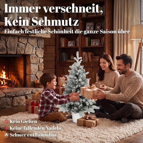 Familie feiert Weihnachten vor einem Kamin mit einem künstlichen, beschneiten Weihnachtsbaum im Topf, der nicht nadelt und schwer entflammbar ist.