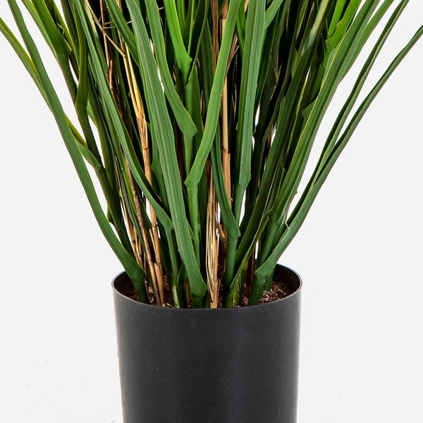 Künstliche Graspflanze in einem schwarzen zylindrischen Topf