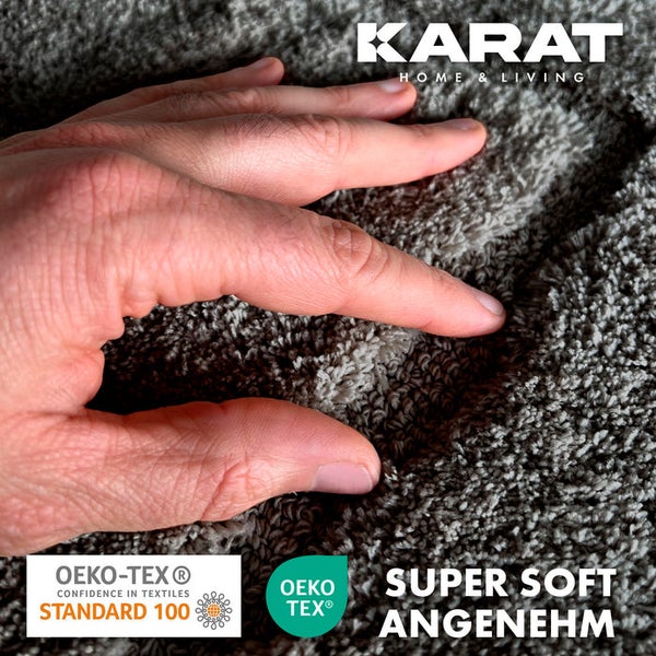 Nahaufnahme eines weichen Teppichs mit Hand und dem Karat Home and Living Logo sowie dem Oeko-Tex Standard 100 Siegel.