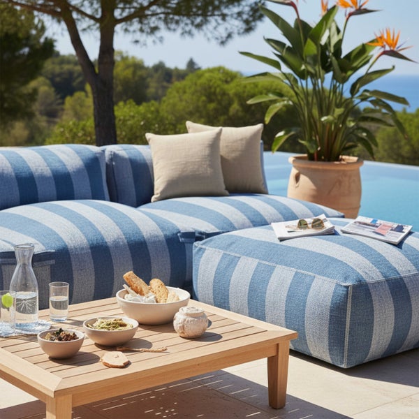 Modernes Garten Lounge Set mit blau weiß gestreiften Polstermöbeln, Holztisch und großer Topfpflanze auf einer sonnigen Terrasse am Pool.