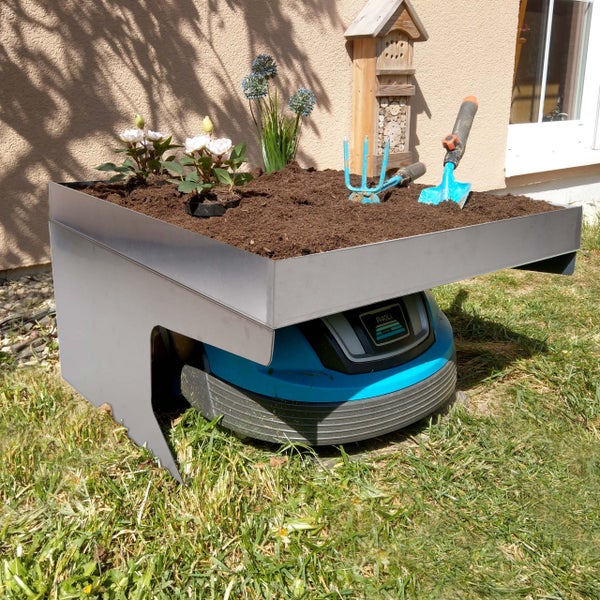 Gardena Mähroboter Garage mit Bepflanzung und Gartenzubehör im Garten