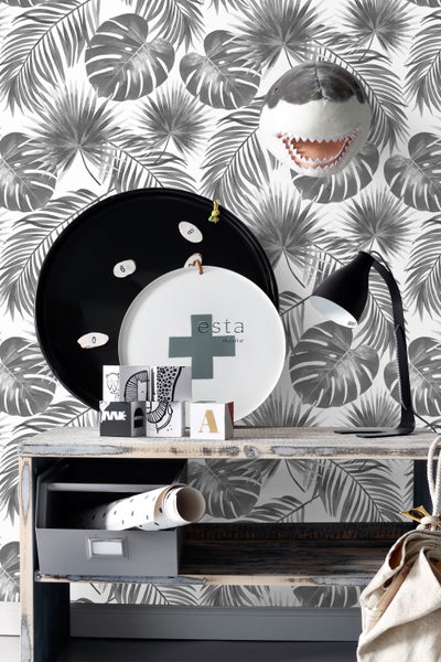 Dekoratives Stillleben mit Tablett, Lampe, Dekowürfeln und Tapete mit Pflanzenmuster auf einem Tisch