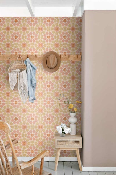 Vliestapete mit geometrischem Sternenmuster in einem hellen Zimmer mit Holzgarderobe, Beistelltisch und Holzstuhl.