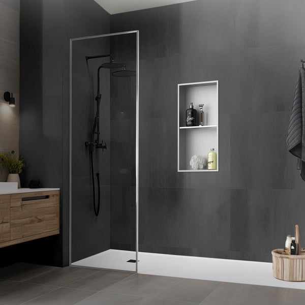 Begehbare Dusche mit Glaswand, schwarzem Duschsystem, weißer Duschwanne und integrierter Wandnische in einem modern gefliesten, dunklen Badezimmer.