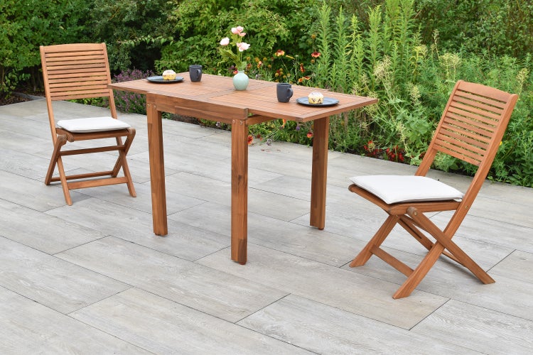 Gartenset mit Holztisch und zwei Klappstühlen mit Auflagen auf einer Terrasse