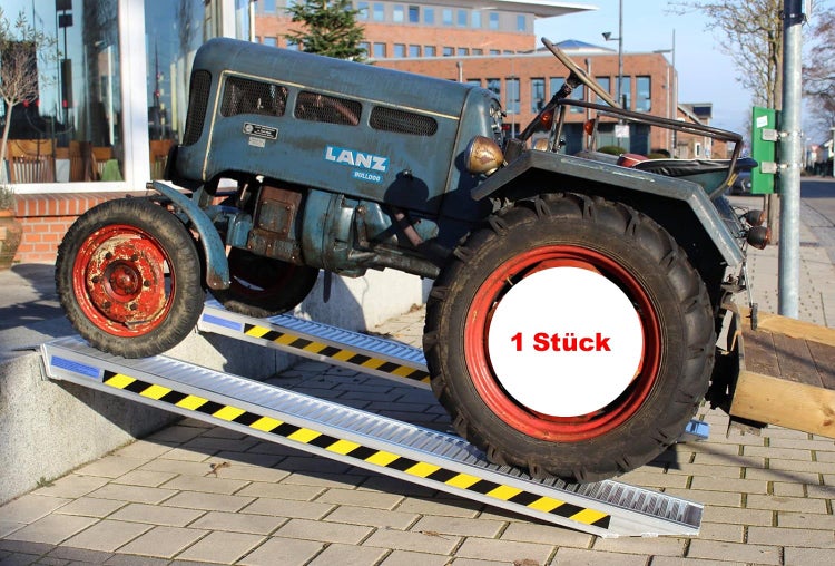 Ein Traktor fährt eine Aluminium Rampe hoch.