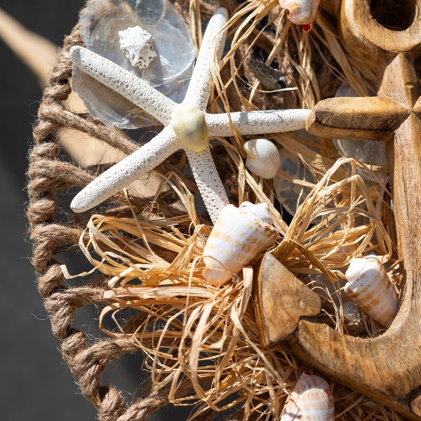 Dekoratives maritimes Arrangement mit Seesternen, Muscheln, Holzanker und Seil