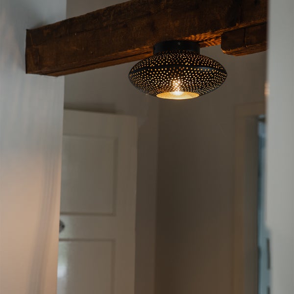 Deckenleuchte mit Lochmuster unter Holzbalken