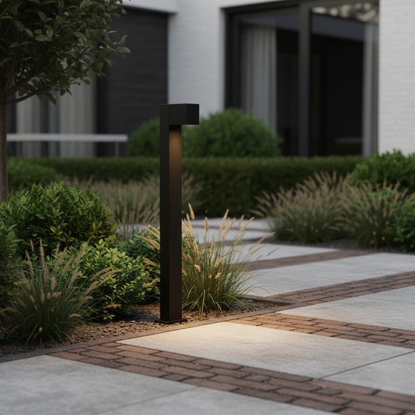 Moderne rechteckige Wegeleuchte im Garten, Lichtschein auf Gehwegplatten und Gräser.