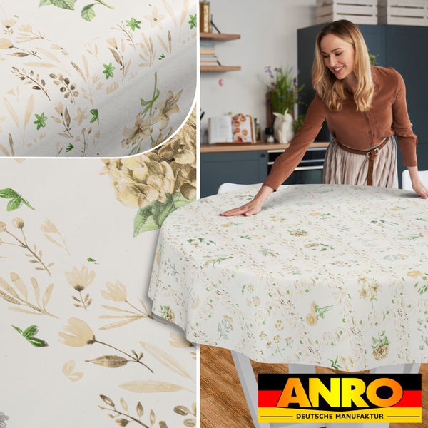 Runde Tischdecke mit botanischem Blumenmuster in Beige- und Grüntönen auf hellem Grund in einer Küche. ANRO Deutsche Manufaktur Logo.