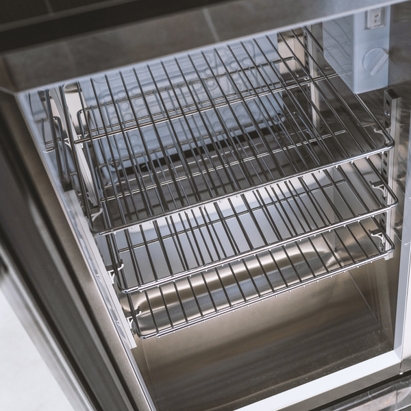 Blick in den Innenraum eines Kühlschranks mit drei höhenverstellbaren Gitterablagen aus Metall und einer Innenverkleidung aus Edelstahl.