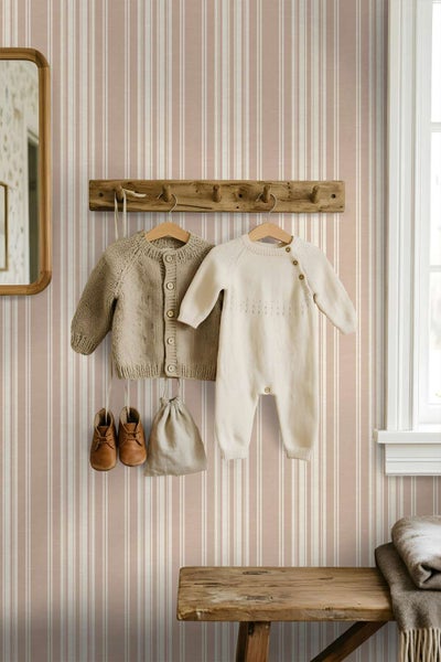Eine Wand mit gestreifter Tapete in einem Kinderzimmer mit einer Holzgarderobe an der Wand und einem Holzhocker im Vordergrund
