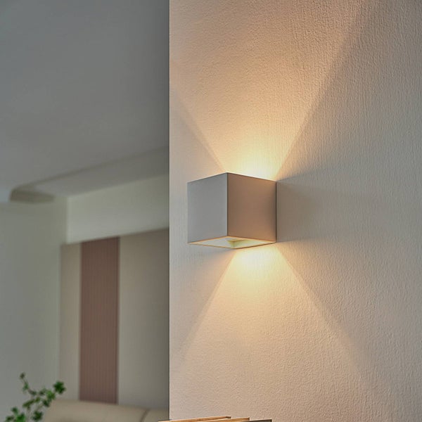 Moderne würfelförmige Wandleuchte mit Lichtaustritt nach oben und unten, an einer Wand montiert.