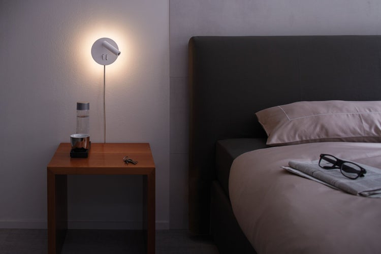 Schlafzimmer mit Bett, Nachttisch und Wandleuchte